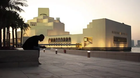 Man using mobile  with the museum of islamic art in the background Stock Footage 68526706