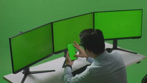 Man Using Mobile Phone And Multiple Computer Monitor With Mock Up Green Video stock 249634374