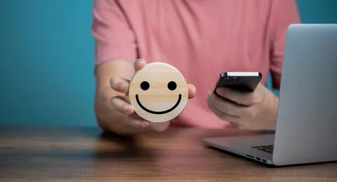 Man using Mobile Phone and holding wooden disc with smiling face icons, custo Stock Photos