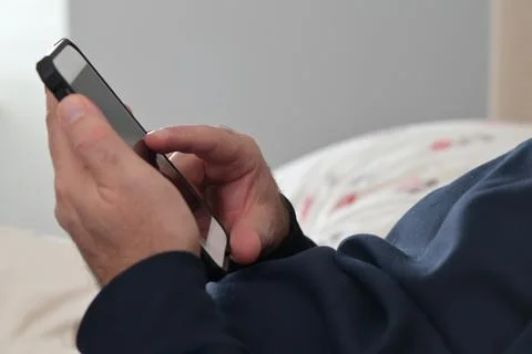 Man using mobile phone in bed. Stock Photos