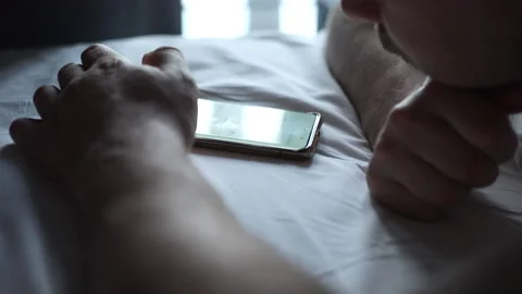 Man using mobile phone, browsing internet and texting on phone lying in bed Stock Footage 171980654