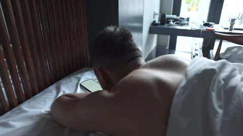 Man using mobile phone, browsing internet and texting on phone lying in bed Stock Footage 171980800