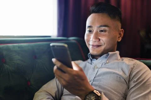Man using a mobile phone on a couch Stock Photos