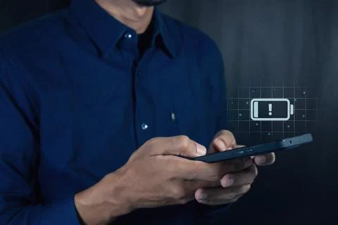 Man using a mobile phone with with a low battery charge icon on the virtual.. Stock Photos