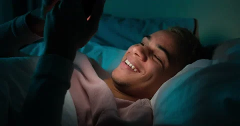 Man using mobile phone lying on bed at night Stock Footage 145291836