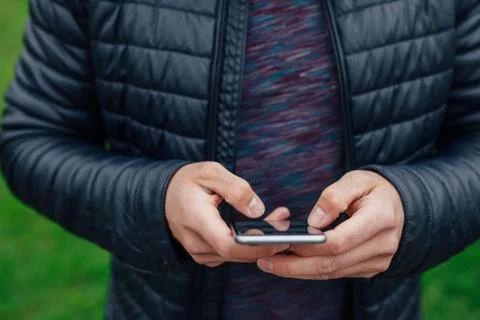 Man using mobile phone in the park. Close up. Stock Photos