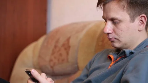 Man using mobile phone sitting at home. Video stock 72561801