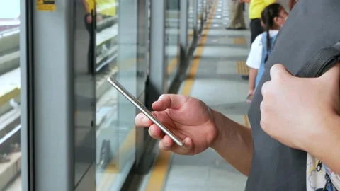 A man using mobile phone waiting for skytrain approaching Stock Footage 142586173