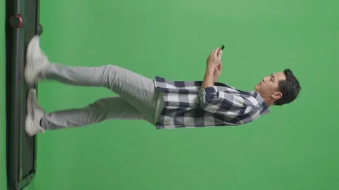 Man Using Mobile Phone While Walking On Green Screen In The Studio Stock Footage 248007294