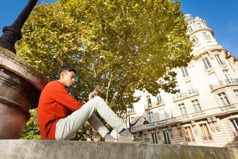 Man using mobile phone while sitting on sidewalk Foto stock