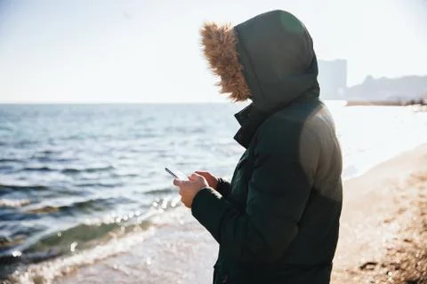 Man using mobile phone while standing on the beach Stock Photos