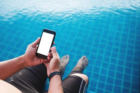 A man using mobile smart phone, blank space on screen, with legs dipping in pool Stock Photos