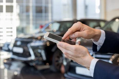 Man using mobile smart phone at dealer showroom. Stock Photos