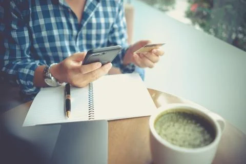 Man using mobile smartphone and credit card for online shopping in coffee sho Stock Photos