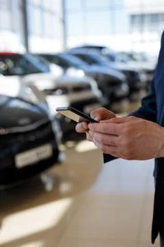 Man using mobile smartphone for communication at dealer showroom. Stock Photos