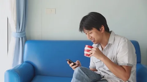 Man using mobile while drinking coffee happiness with socila media at home Video stock 126198027