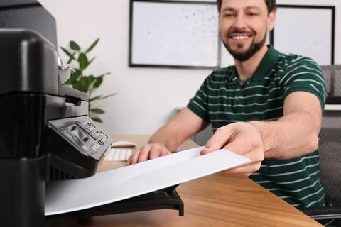 Man using modern printer at wooden table indoors, selective focus Stock Photos