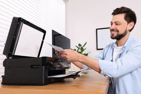 Man using modern printer at wooden table indoors Stock Photos