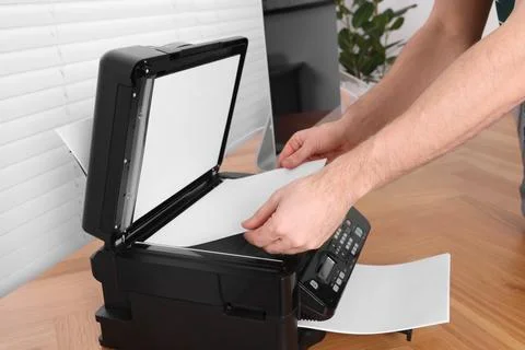 Man using modern printer at wooden table indoors, closeup Stock Photos