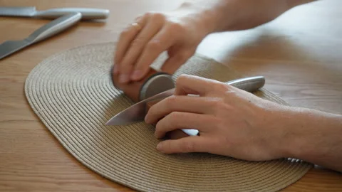 Man using a modern rolling knife sharpener to hone a kitchen knife blade Stock Footage 315209373