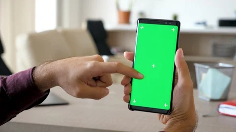 Man using a modern smartphone with green screen chroma mock-up in his living Stock Footage 95676997