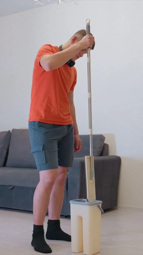 Man Using Mop and Bucket for Floor Cleaning in Modern Living Room showing orange Stock Footage 346790943