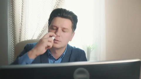 Man using nasal medicine while working at computer Stock Footage 171963683