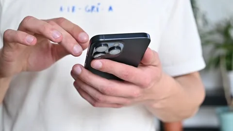 Man using a new mobile phone, iphone 15 close-up, scrolling Stock Footage 273974332