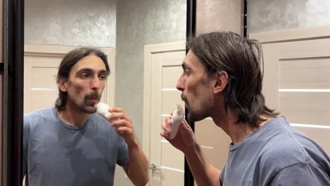 Man using a nose hair trimmer in a bathroom while looking at himself in mirror Stock Footage 282513850