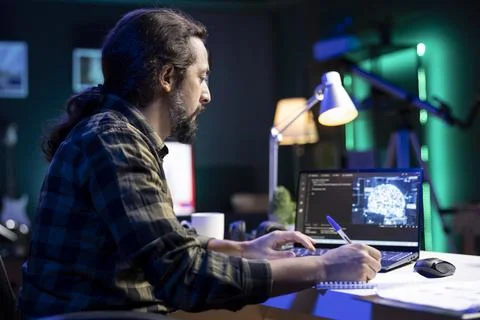 Man using notepad and laptop for coding 库存照片