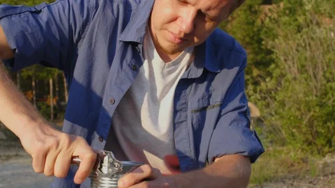 Man using opener for canned goods in forest Vidéo 118548431