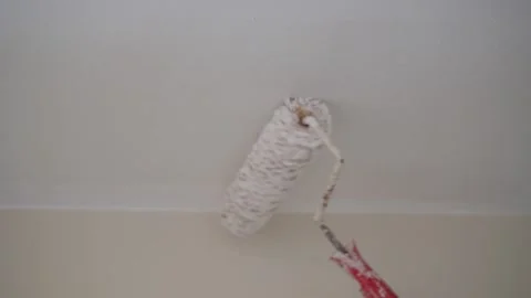 A man is using a paint roller to apply paint to a wall inside a room Stock Footage 347502591