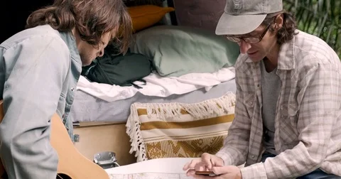 Man using a paper map and smart phone with his friend while camping Stock Footage 80809603