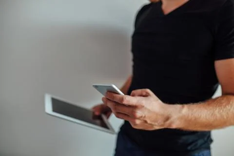 Man is using pc tablet and holding phone. Stock Photos