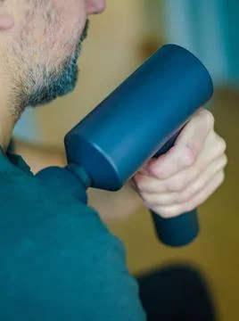 Man Using Percussion Massage Gun for Shoulder Muscle Relief Stock Photos