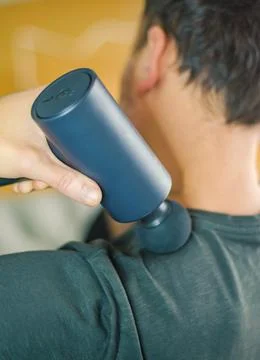 Man Using Percussion Massage Gun for Shoulder Muscle Relief Stock Photos