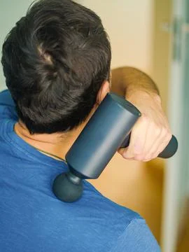 Man Using Percussion Massage Gun for Shoulder Muscle Relief Stock Photos