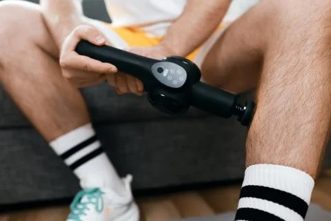Man using a percussion massage gun on his calf for muscle tension relief an.. 写真素材
