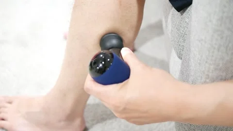 Man using percussion massager on calves muscle Stock Footage 246580236