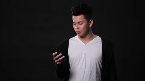 A Man Using a Phone Against a Black Background Stock Footage 87263796