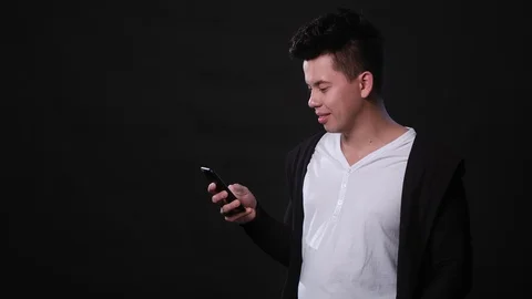 A Man Using a Phone Against a Black Background Stock Footage 87278908