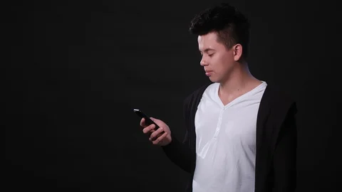 A Man Using a Phone Against a Black Background Stock Footage 87280541