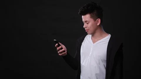 A Man Using a Phone Against a Black Background Stock Footage 87285700