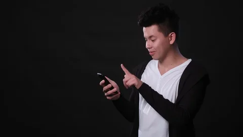 A Man Using a Phone Against a Black Background Stock Footage 87285990