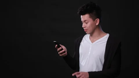 A Man Using a Phone Against a Black Background Stock Footage 87286158