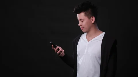 A Man Using a Phone Against a Black Background Stock Footage 87286644