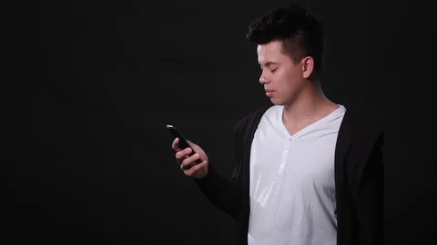 A Man Using a Phone Against a Black Background Stock Footage 87287153