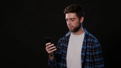 A Man Using a Phone Against a Black Background Stock Footage 88377848