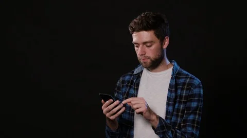 A Man Using a Phone Against a Black Background Stock Footage 88379925