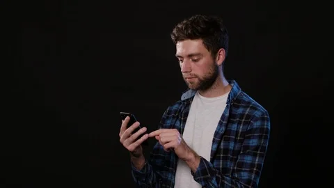 A Man Using a Phone Against a Black Background Stock Footage 88380694